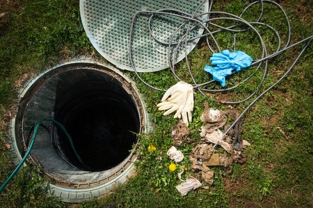 Gloves and a hose next to a septic system